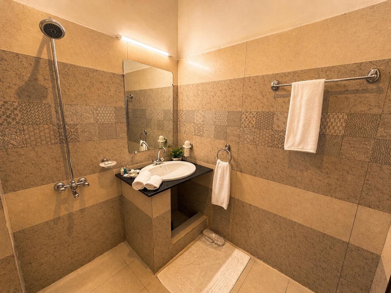 En-suite bathroom with patterned stone tiling, rain shower and vanity